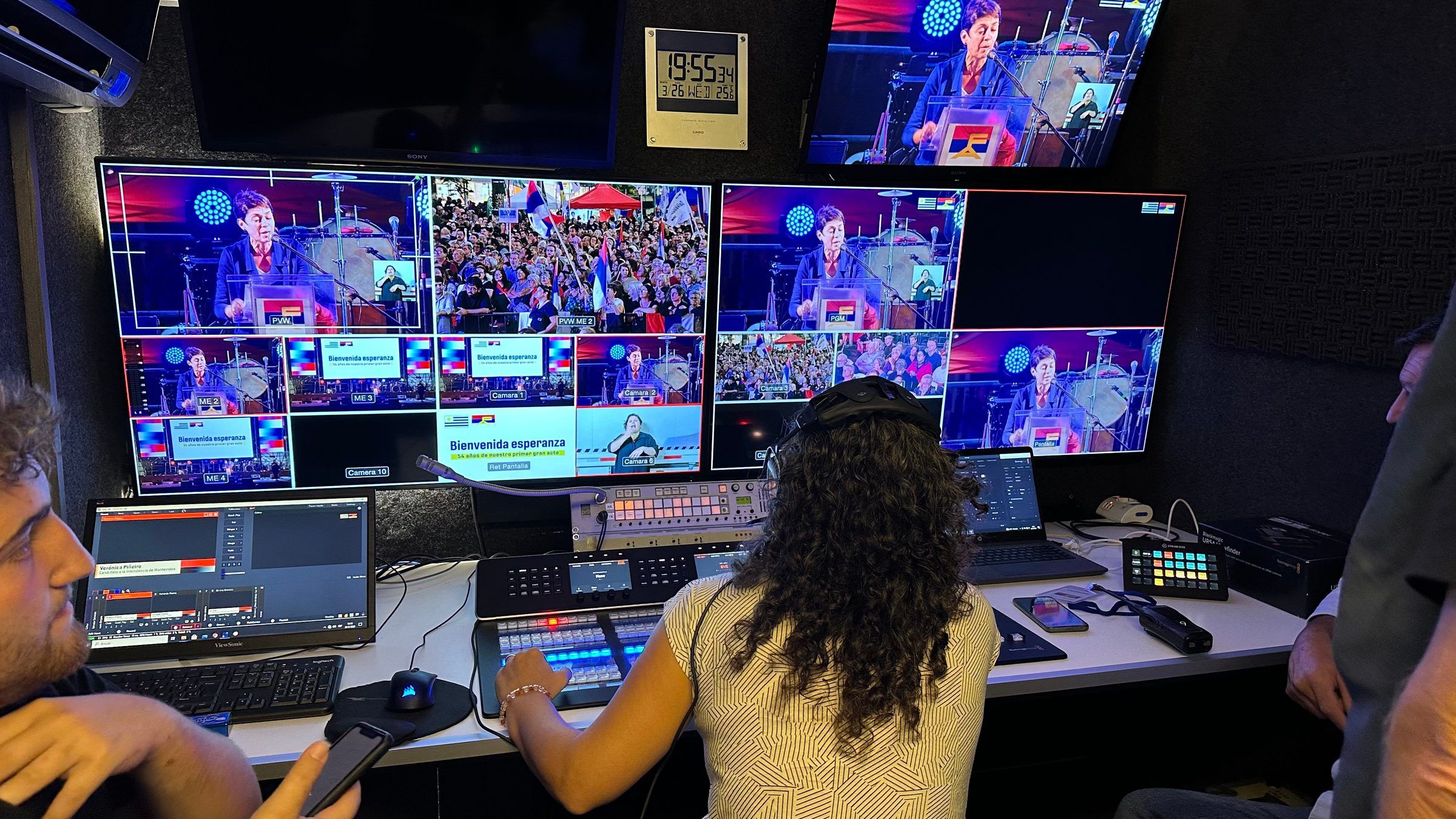 Realizadora operando el mezclador en el móvil de control durante el acto, con la multipantalla de cámaras.