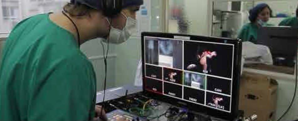 Realizador con auriculares y ropa de quirófano ante un monitor con las distintas cámaras de una operación
