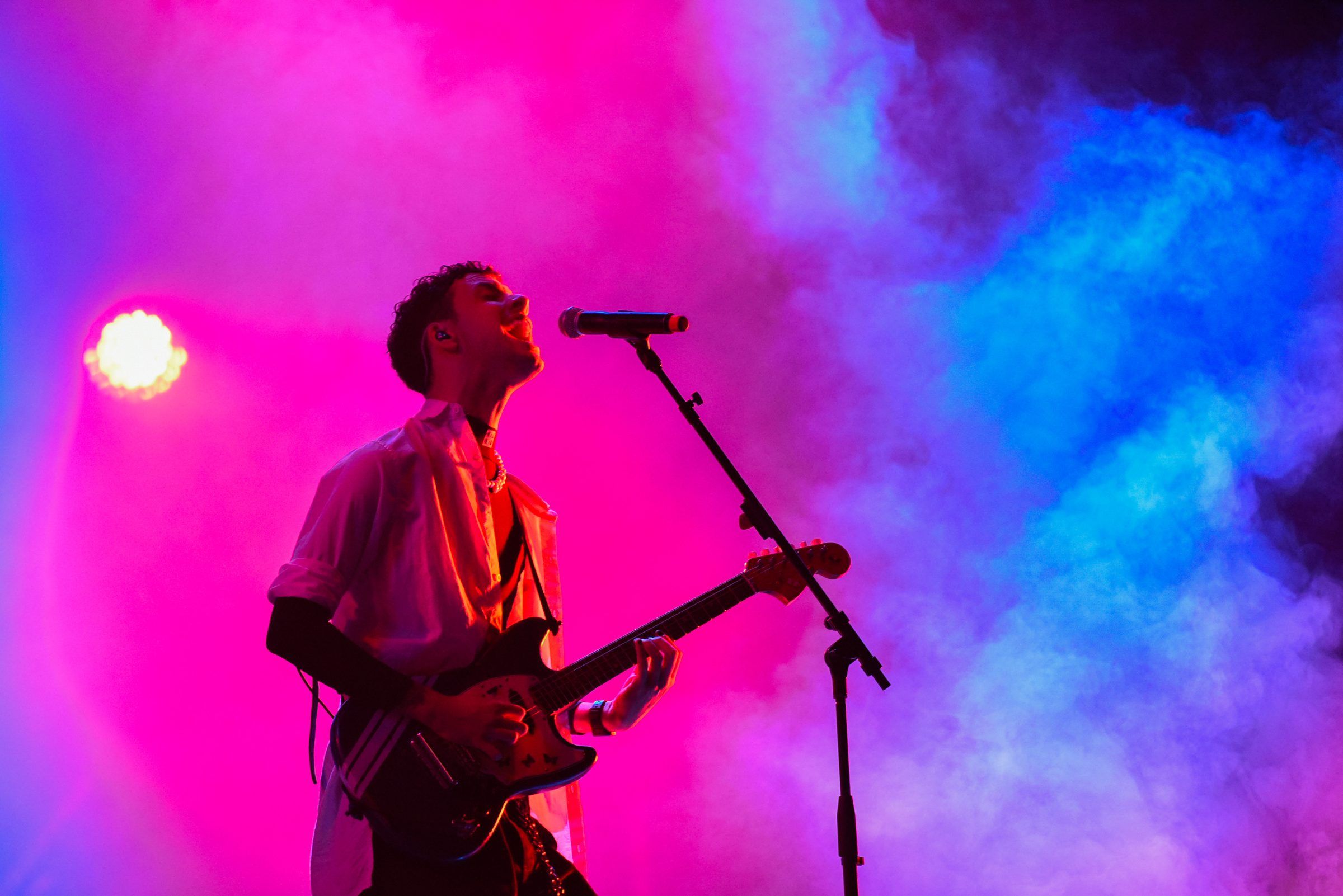Guitarrista en el escenario del Cosquín Rock Uruguay 2023, con humo e iluminación rosa