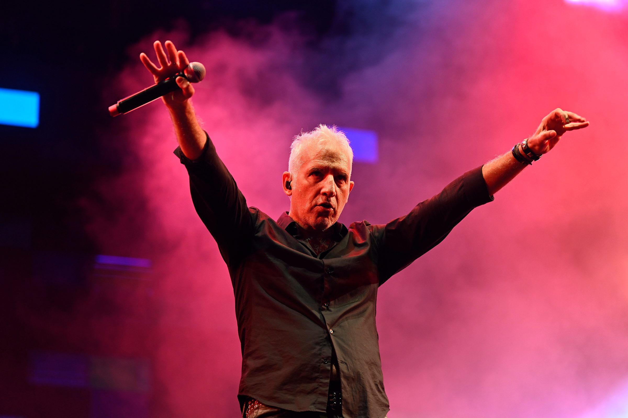 El cantante de Buitres con los brazos abiertos en el escenario del Cosquín Rock Uruguay 2024, entre humo rosado