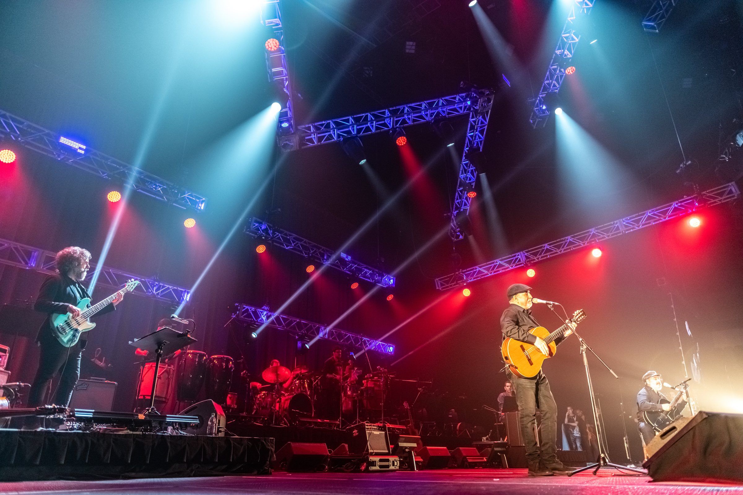 Larbanois & Carrero en el escenario con la banda, bajo estructuras de iluminación roja y azul