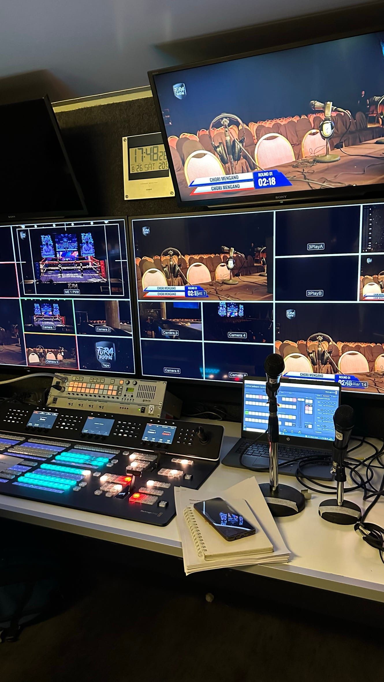 Mesa de control de la transmisión con mezclador y monitores que muestran la pelea