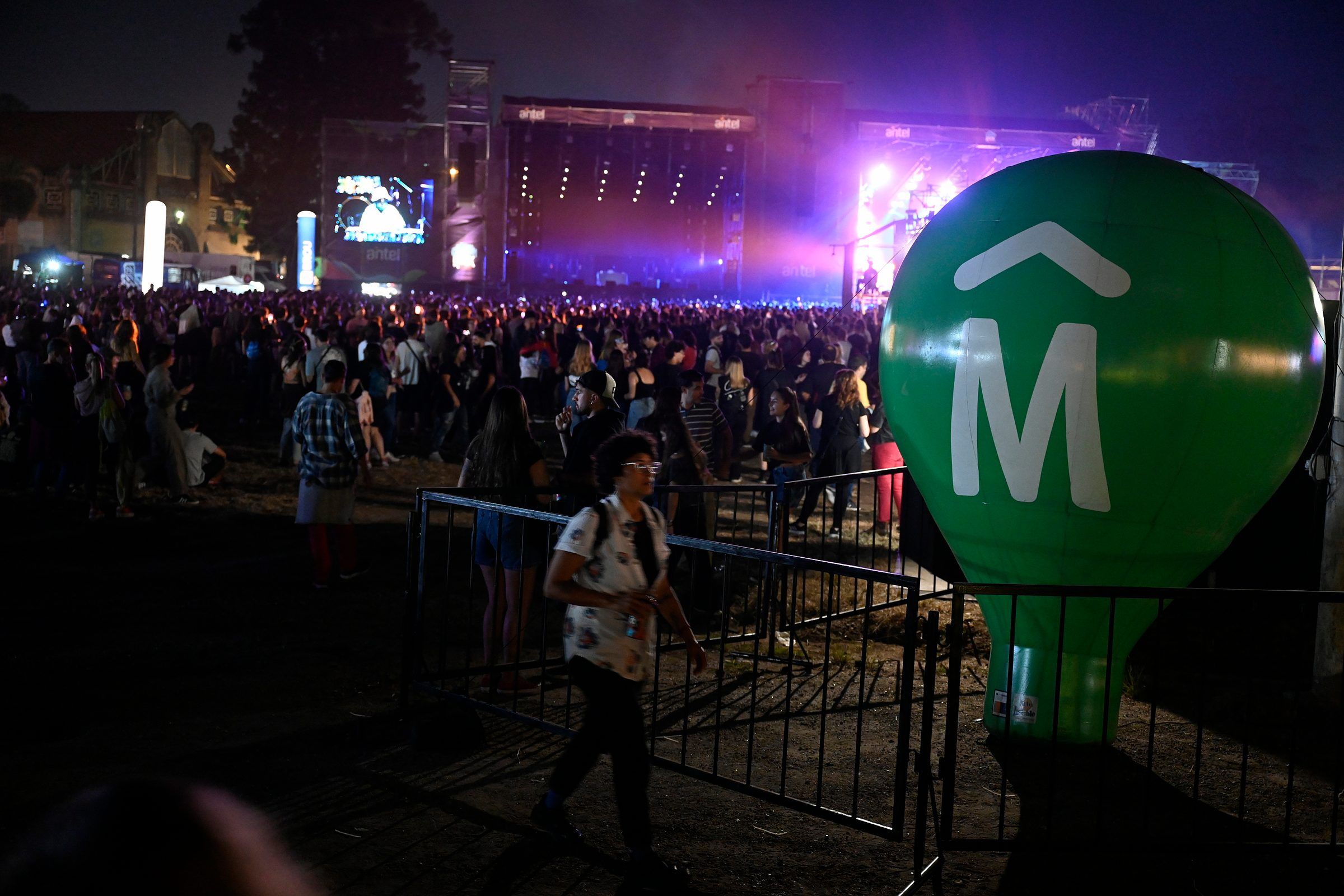 Vista nocturna del predio del Cosquín Rock Uruguay 2024, con el escenario al fondo y el público