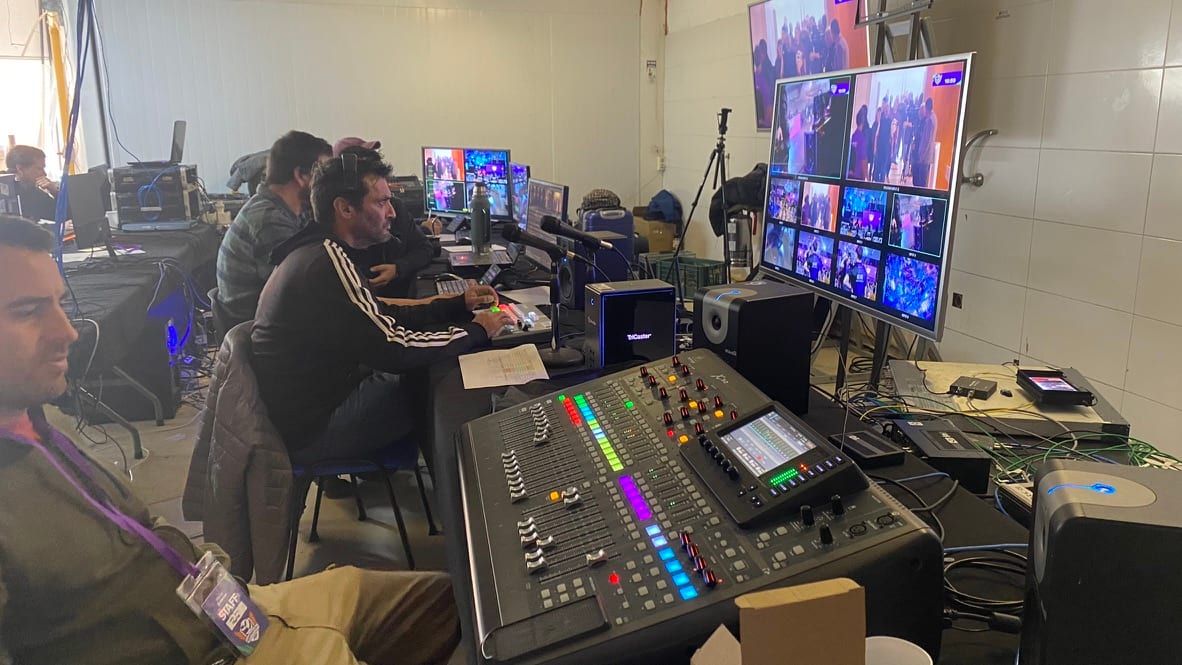 Equipo técnico en la mesa de control con mezclador de audio y monitores de multivisión