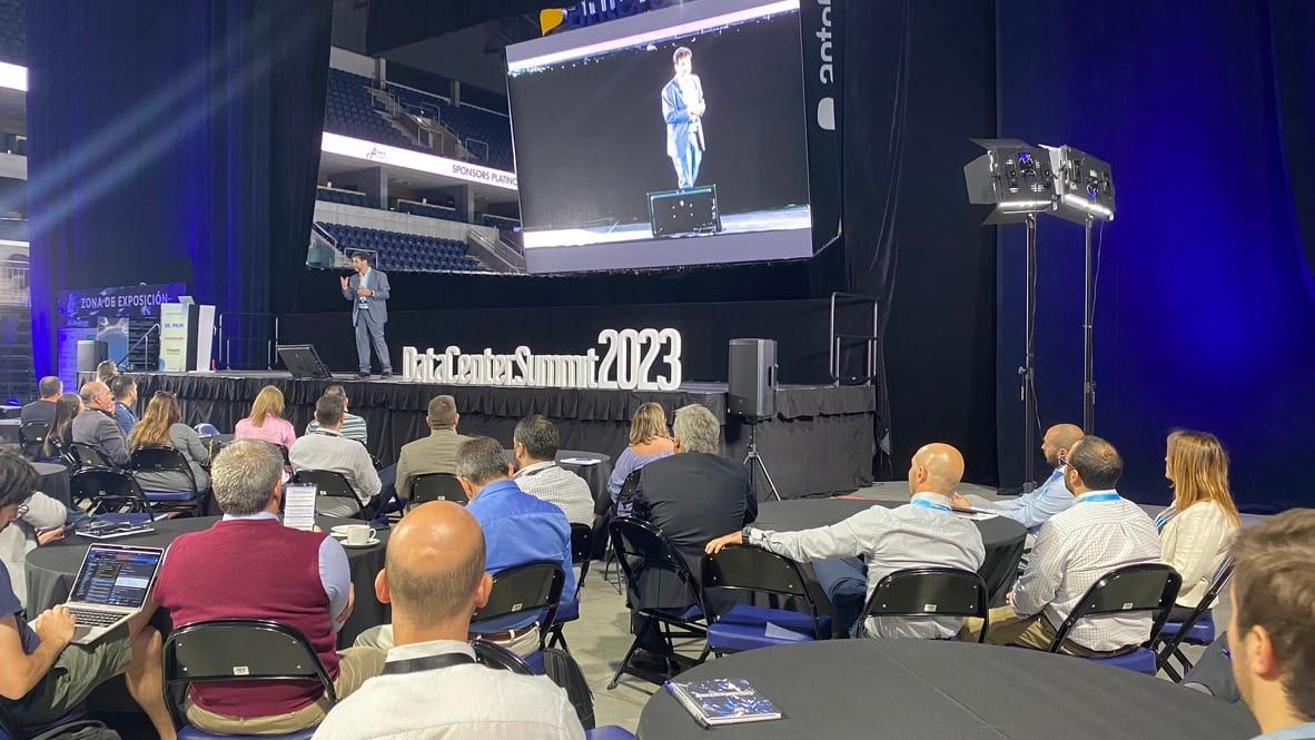 Primer plano del escenario del Data Center Summit 2023 con el orador y la pantalla del Antel Arena