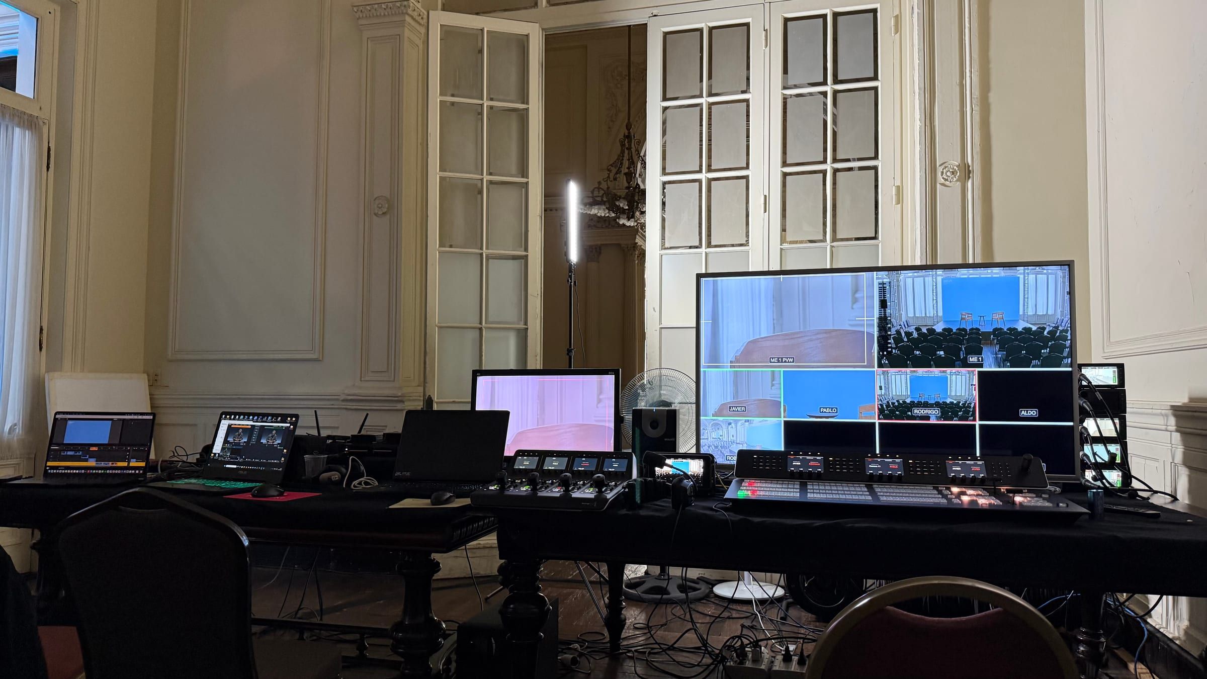 Mesa de realización con monitores y mezclador de video instalada al fondo del salón