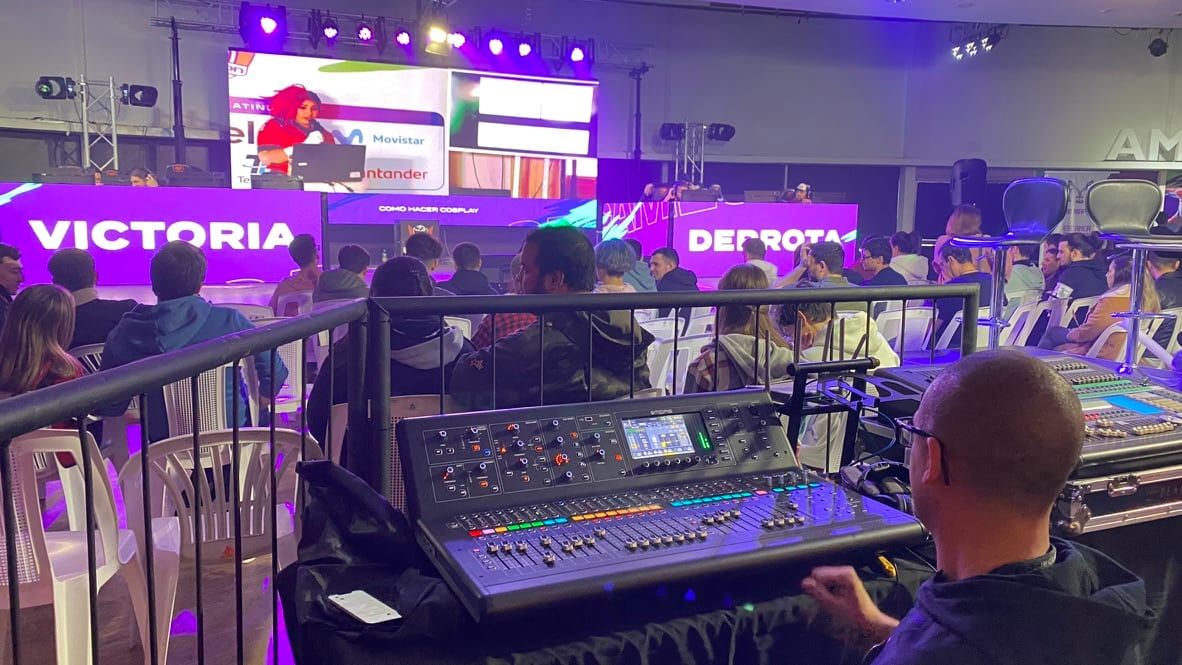 Mesa de sonido frente al escenario de Gamecon 2022, con pantallas de «Victoria» y «Derrota»