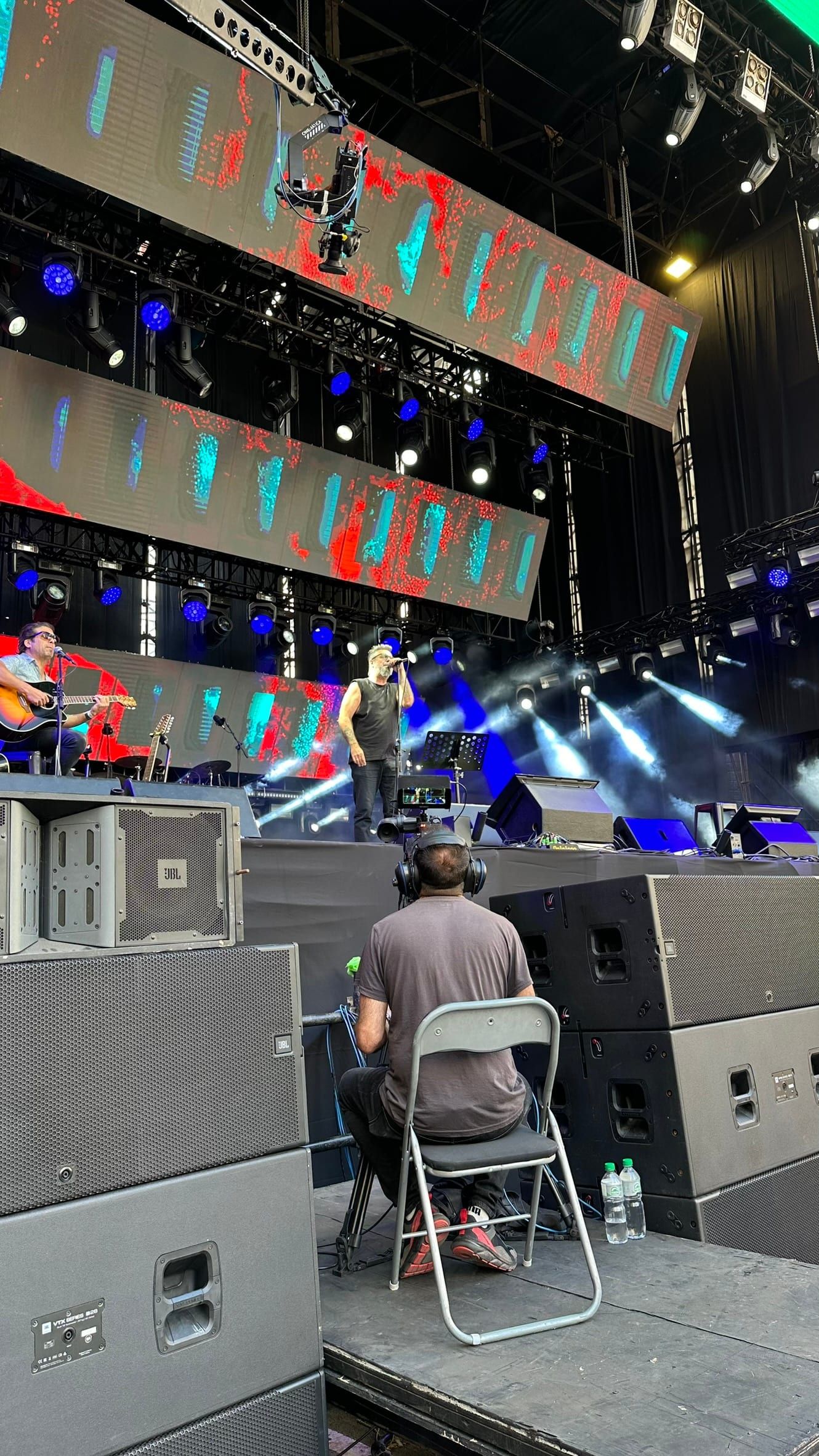 Artista tocando la guitarra en un escenario con pantallas de led, durante los festejos por los 300 años de Montevideo.