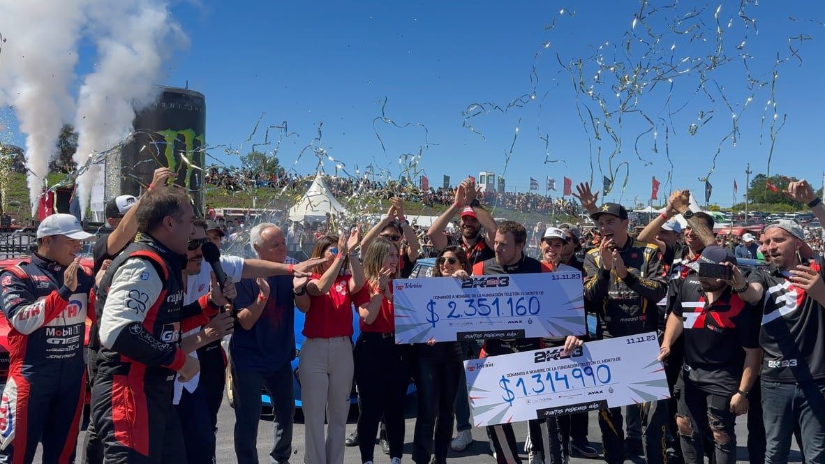 Festejo con humo y papel picado en el evento de drifting, con pilotos y organizadores sosteniendo dos cheques grandes