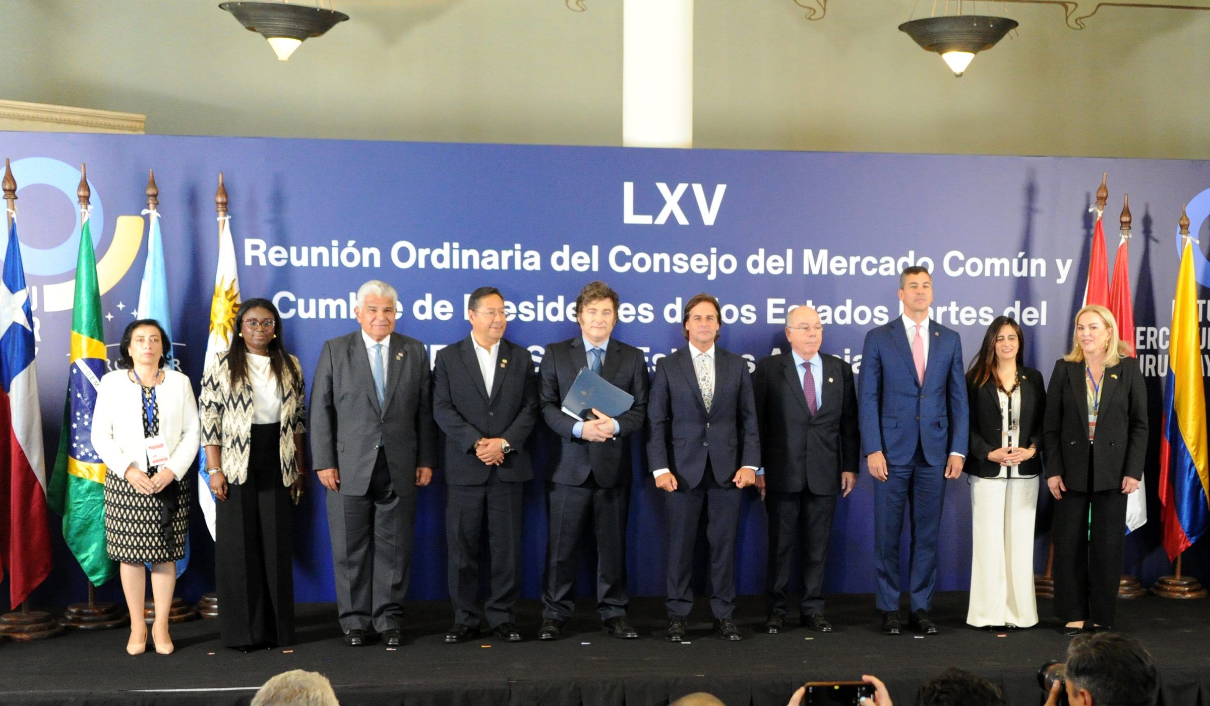 Foto de familia de los mandatarios y delegaciones frente al panel de la LXV reunión del Consejo del Mercado Común.