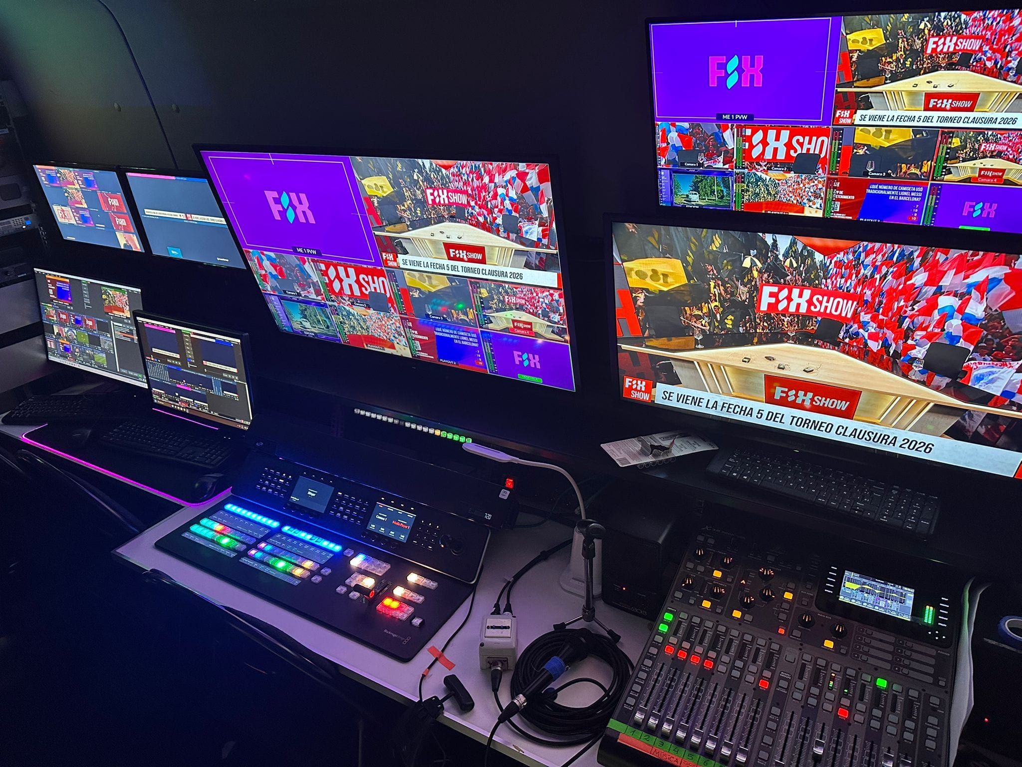 Puesto de control dentro de la minivan: mezcladora de video y consola de audio frente a una pared de monitores